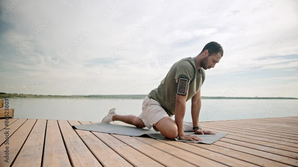 African American man stretching on pierce. Practicing yoga next to beautiful lagoon. Relaxing muscles before active exercise. Preparing his body and mind . Concept of active lifestyle. African American man stretching on pierce. Practicing yoga next to beautiful lagoon. Relaxing muscles before active exercise. Preparing his body and mind . Concept of active lifestyle.