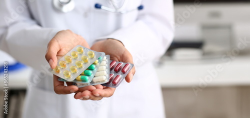 Female doctor hand holding pack of different tablet blisters at workplace closeup. Panacea life save service prescribe medicament legal drug store disease healing blood pressure concept