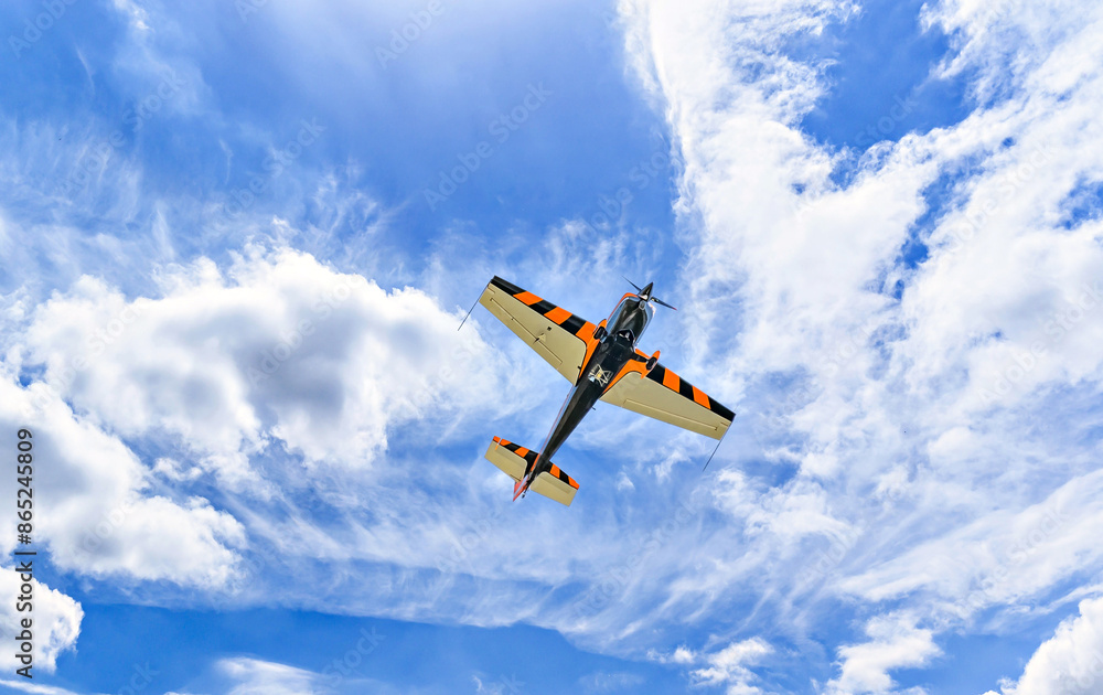 View of an aerobatic plane (aerodyne), in flight under a blue sky with white clouds. flight exhibitions View of an aerobatic plane (aerodyne), in flight under a blue sky with white clouds. flight exhibitions