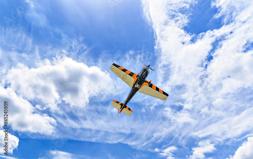 View of an aerobatic plane (aerodyne), in flight under a blue sky with white clouds. flight exhibitions 