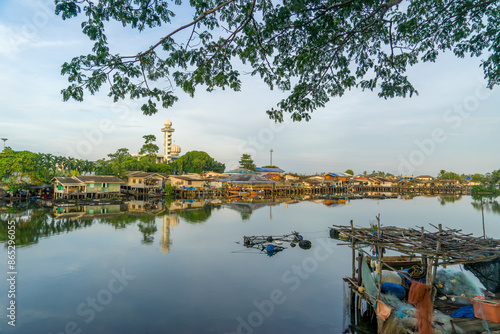 Local fishing village along the Bang Nara River with kolae boats colorful with a mosque in the background in the evening.
