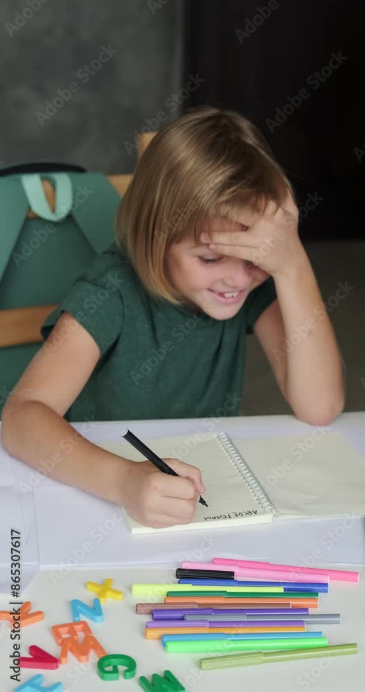 Vertical video of a little boy from elementary school doing his homework with a smile and joy. He talks to his mother and laughs as he writes an alphabet in his notebook. Happy to be back at school. Vertical video of a little boy from elementary school doing his homework with a smile and joy. He talks to his mother and laughs as he writes an alphabet in his notebook. Happy to be back at school.