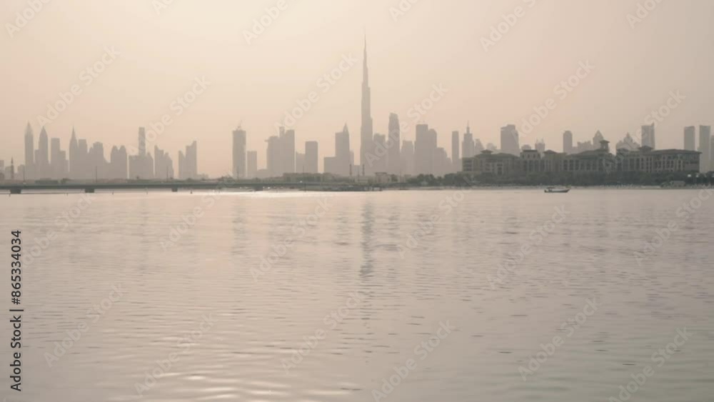 Dubai city skyline is seen at dawn, with the tallest building dominating the horizon. The scene is reflected in the calm waters of a lake, creating a symmetrical and tranquil image Dubai city skyline is seen at dawn, with the tallest building dominating the horizon. The scene is reflected in the calm waters of a lake, creating a symmetrical and tranquil image