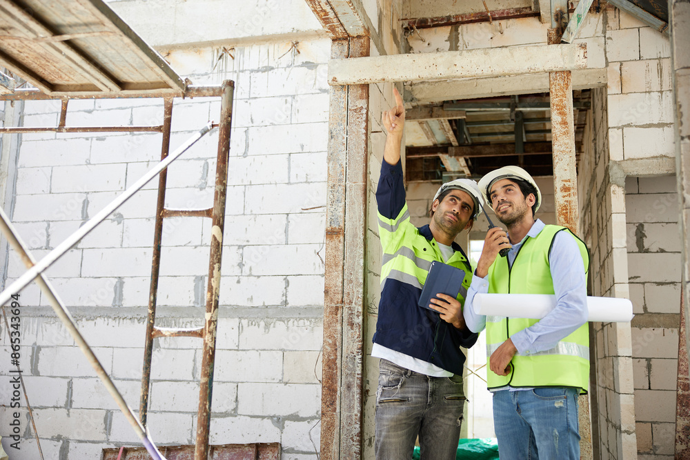 workers or architects working on tablet and pointing up to something at construction site workers or architects working on tablet and pointing up to something at construction site