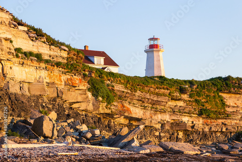 Low angle view of the remote Île aux Perroquets (Parrots Island) lighthouse and rocks fallen from the cliff seen from the beach in the Mingan Archipelago National Park Reserve, Quebec, Canada photo