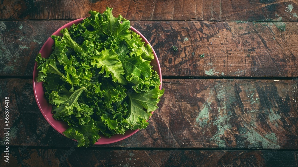 Artistic arrangement of organic kale leaves in a stylish pink bowl, enhancing the natural appeal of a wooden surface Artistic arrangement of organic kale leaves in a stylish pink bowl, enhancing the natural appeal of a wooden surface