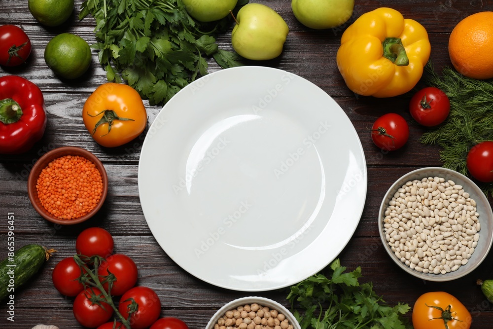 Different vegetarian products and plate on wooden table, top view Different vegetarian products and plate on wooden table, top view