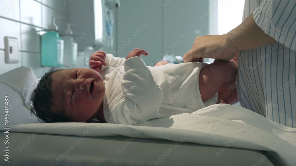 Obraz premium Newborn baby being dressed in a white outfit by a parent, lying on a hospital changing table, highlighting the nurturing care given to infants in a medical setting right after birth