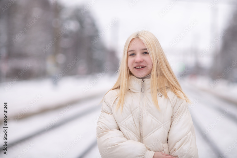 Portrait of a young beautiful blonde girl outdoors in winter in cloudy weather. Portrait of a young beautiful blonde girl outdoors in winter in cloudy weather.