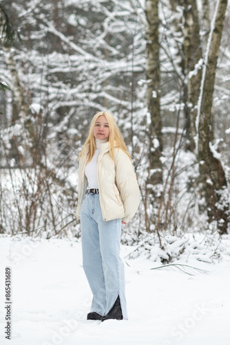 Portrait of a young beautiful blonde girl outdoors in winter in cloudy weather.