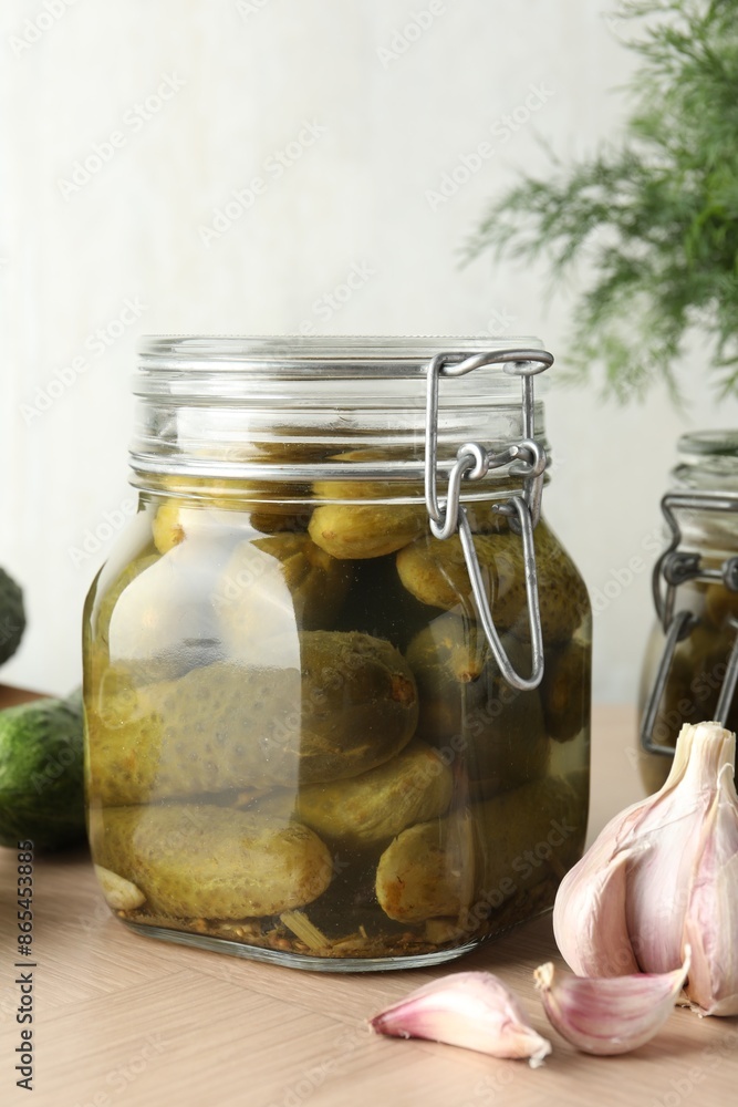 Pickled cucumbers in jar and garlic on wooden table, closeup Pickled cucumbers in jar and garlic on wooden table, closeup