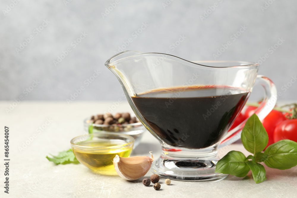 Balsamic vinegar in gravy boat, oil, basil and spices on gray textured table, space for text Balsamic vinegar in gravy boat, oil, basil and spices on gray textured table, space for text