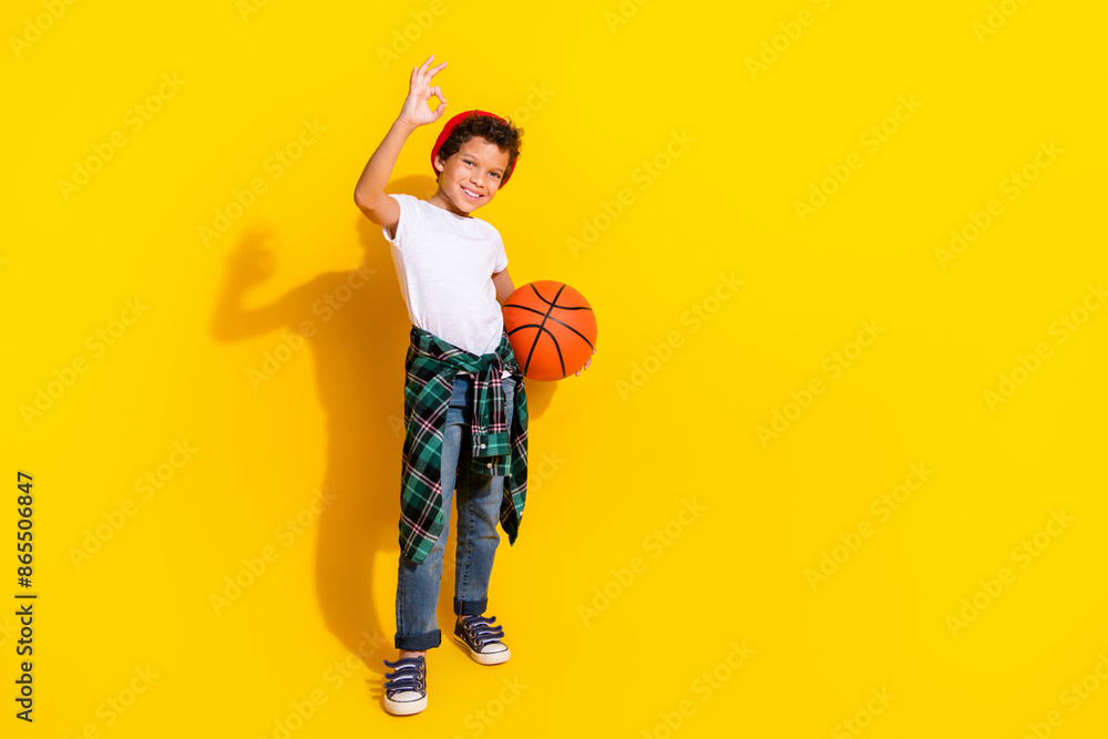 Full size photo of small charming boy basketball ball okey wear trendy white outfit isolated on yellow color background Full size photo of small charming boy basketball ball okey wear trendy white outfit isolated on yellow color background