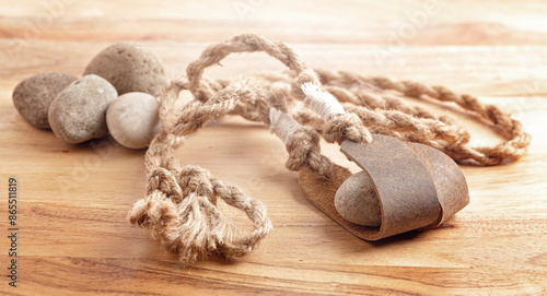 Canvas Print Antique Sling Shot and Stones on a Wooden Table from the Story of David and Goli