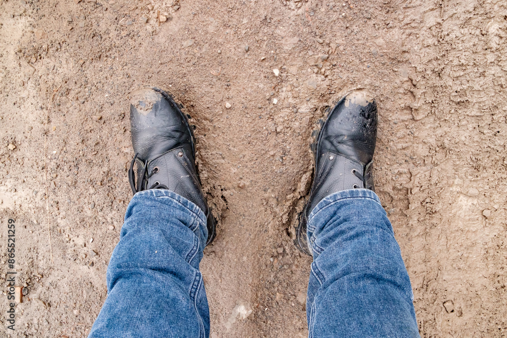 men's feet in jeans and boots standing in the mud, top view men's feet in jeans and boots standing in the mud, top view