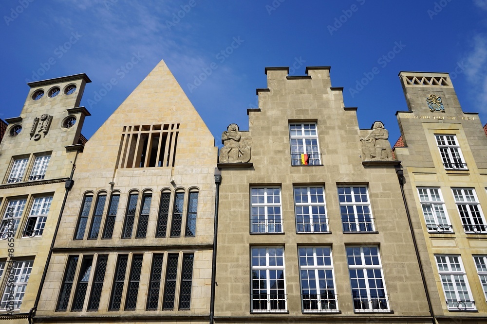 Fototapeta premium Schönes altes Kaufmannshaus und Altbau in Beige und Naturfarben vor blauem Himmel im Sonnenschein am Prinzipalmarkt in der City und Altstadt von Münster in Westfalen im Münsterland
