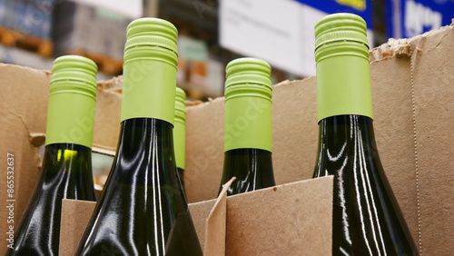 Close-up of a few wine bottles with green caps in a trading box