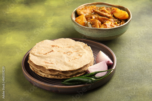 Egg plant and Potato curry bhakri or Indian flat bread served with green chilli chutney traditionally called as Theccha in Marathi and onion beside the plate