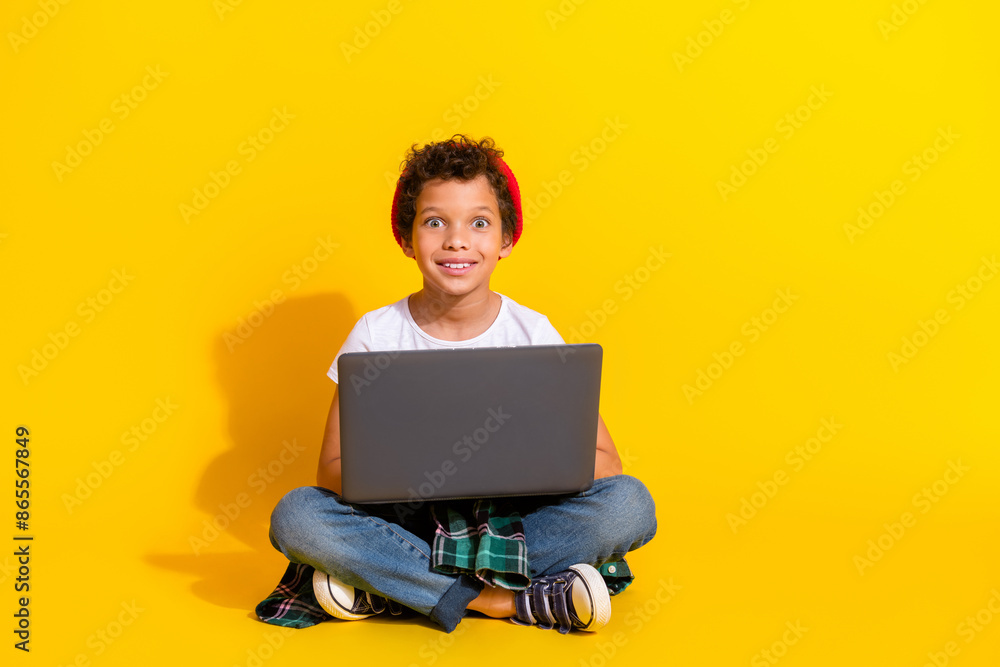 Full length photo of adorable little boy hold netbook ecommerce dressed stylish white garment isolated on yellow color background Full length photo of adorable little boy hold netbook ecommerce dressed stylish white garment isolated on yellow color background