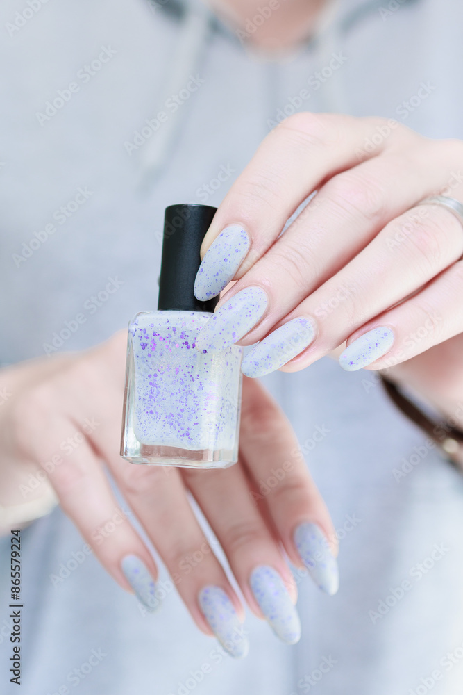 Obraz premium Female hand with long nails and a white gray and purple manicure