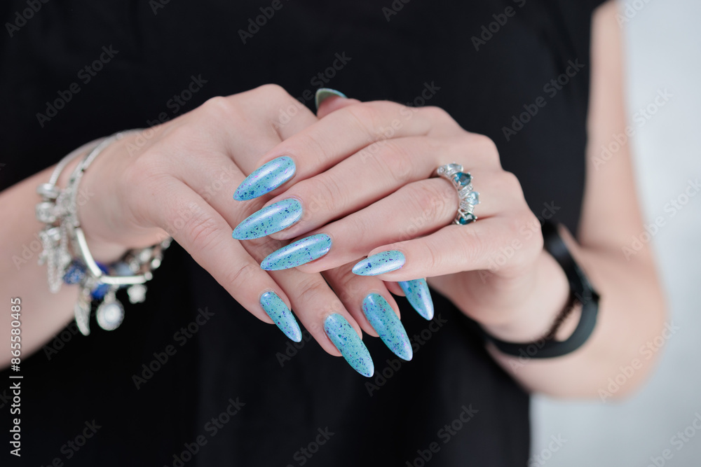 Fototapeta premium Woman's beautiful hand with long nails and light blue manicure