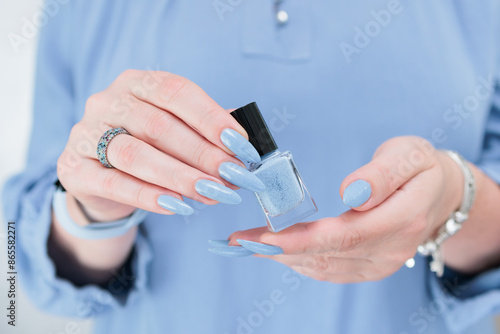 Woman's beautiful hand with long nails and light baby blue manicure