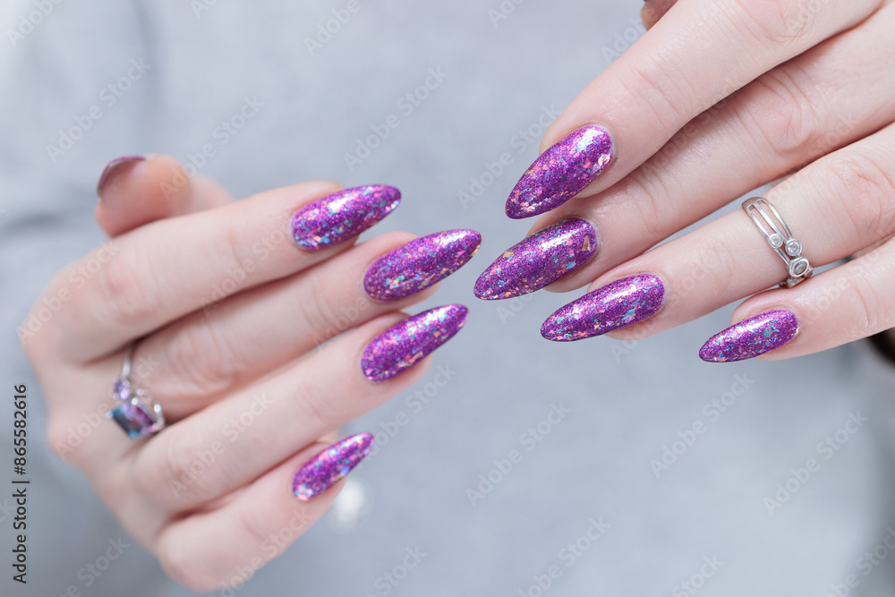 Woman hand with long nails and a bottle of plum purple nail polish Woman hand with long nails and a bottle of plum purple nail polish