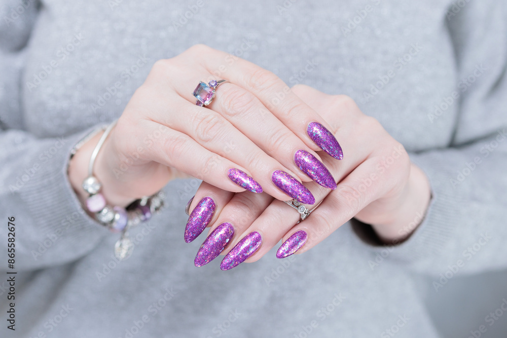 Woman hand with long nails and a bottle of plum purple nail polish Woman hand with long nails and a bottle of plum purple nail polish