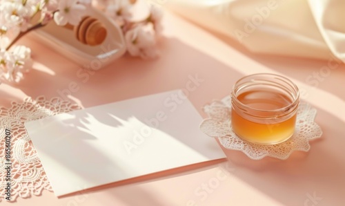 White blank card on a pastel peach table, with a delicate lace doily and a small glass jar of honey photo
