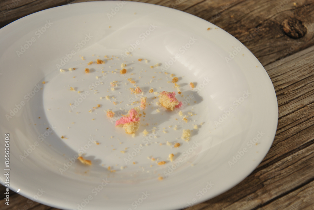 white plate with food crumbs. empty dirty plate on a wooden table. selective focus white plate with food crumbs. empty dirty plate on a wooden table. selective focus