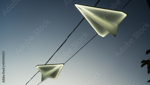 Street lights in the form of paper airplanes, against the background of the sunset sky