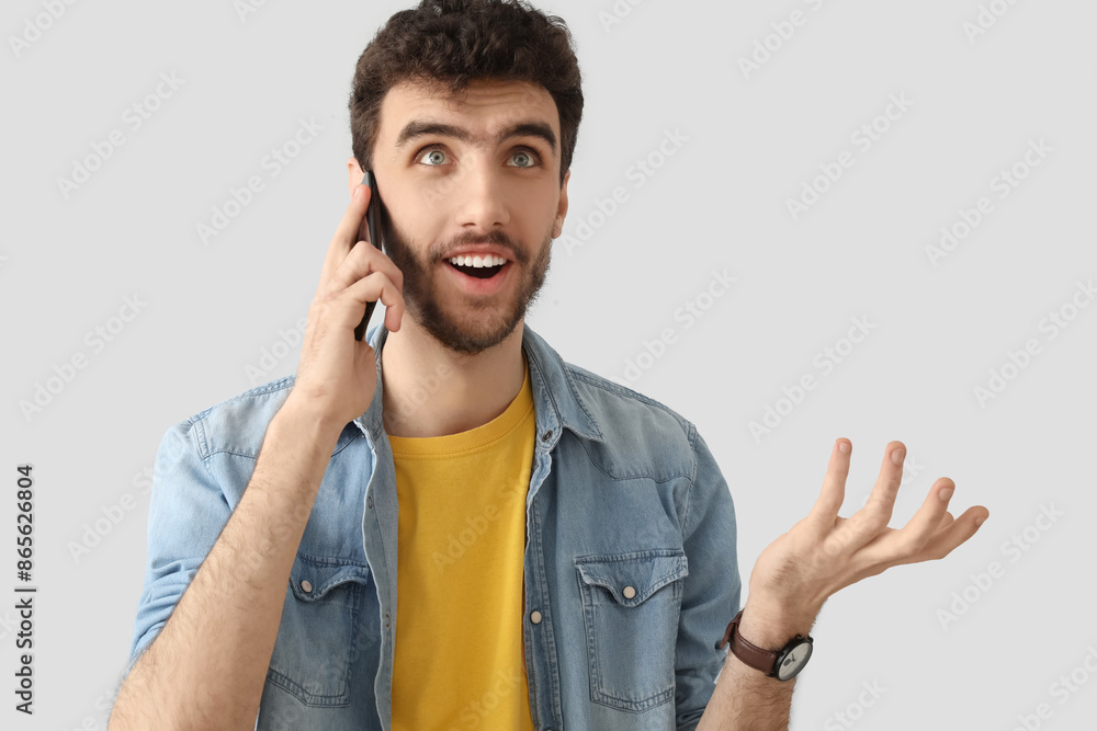 Handsome young man talking by mobile phone on light background Handsome young man talking by mobile phone on light background