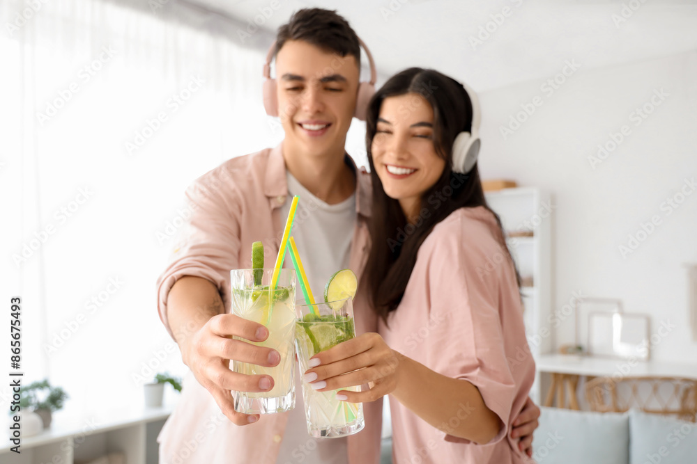 Happy young couple in headphones with glasses of mojito at home Happy young couple in headphones with glasses of mojito at home