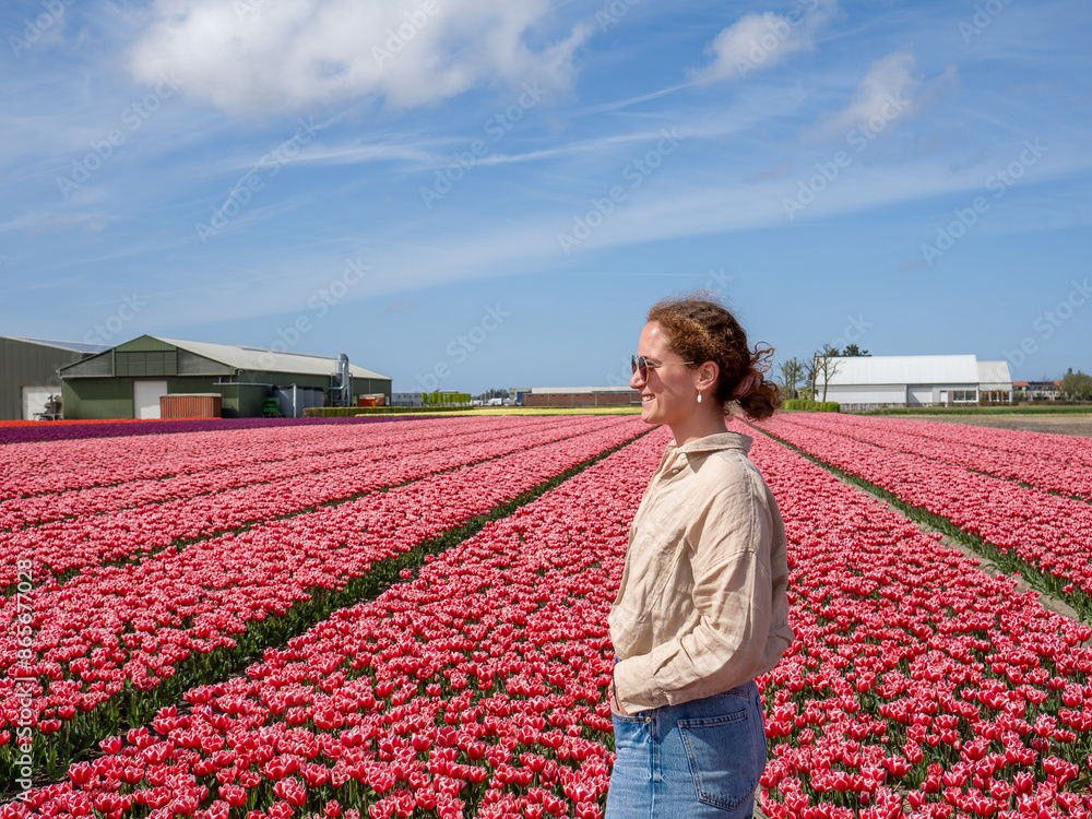 Woman Enjoying a Bright Day in a Vast Tulip Field - Appreciation of Natural Beauty Woman Enjoying a Bright Day in a Vast Tulip Field - Appreciation of Natural Beauty