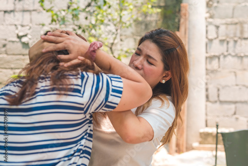 An irate woman pulls the hair of her partner's mistress during a physical altercation outdoors. Overcome with extreme anger.