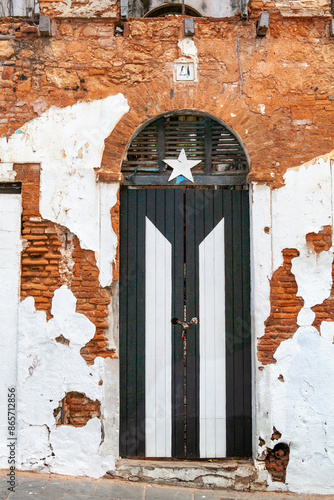 Large weathered black and white door on facade of old abandoned government brick building in Old San Juan, Puerto Rico