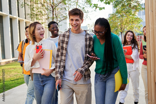 Foto Cheerful group of multi-ethnic students walking towards the camera going to university classes, talking and laughing together