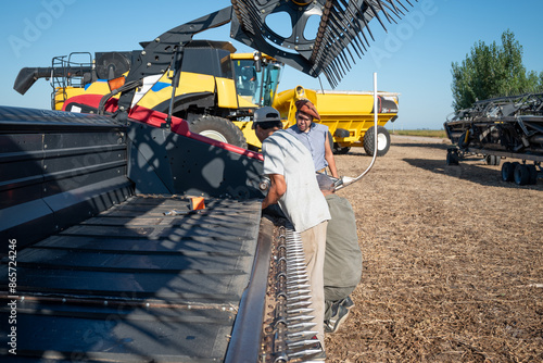 Hombres reparando y poniendo a punto cosechadora de soja, campo argentino, industria