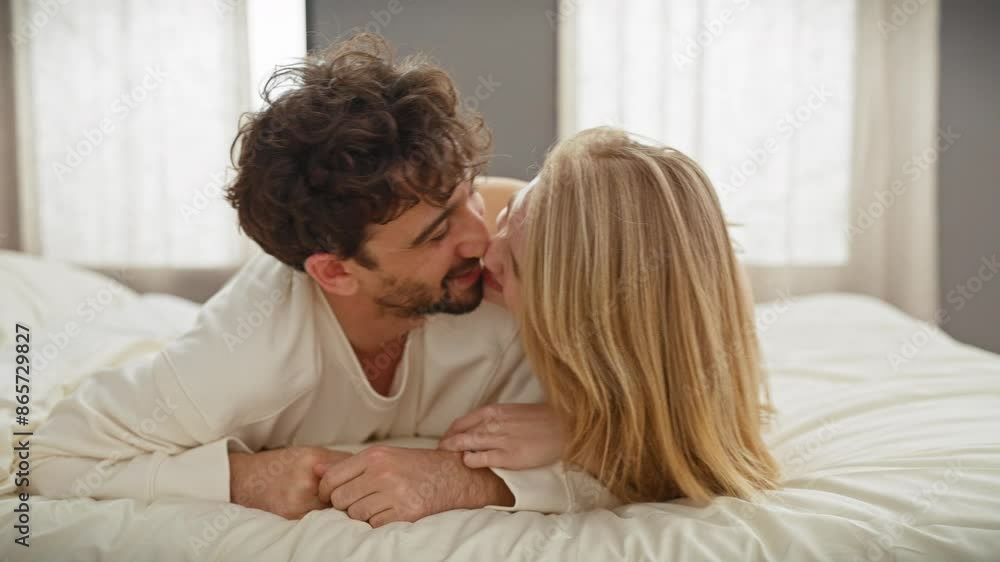 Affectionate man and woman embracing and smiling on a comfortable bed in a bright bedroom setting. Affectionate man and woman embracing and smiling on a comfortable bed in a bright bedroom setting.