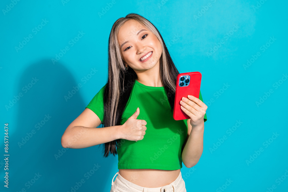 Photo of nice young girl smart phone show thumb up wear green t-shirt isolated on teal color background Photo of nice young girl smart phone show thumb up wear green t-shirt isolated on teal color background