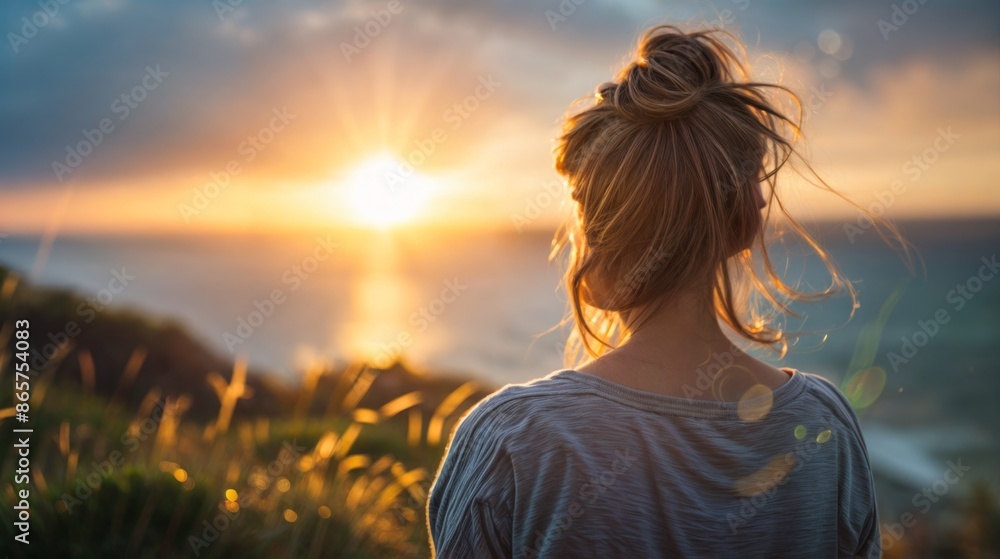 Woman with hair tied up watching the sunset over the ocean Woman with hair tied up watching the sunset over the ocean