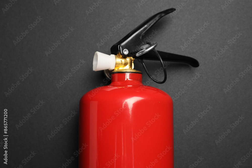 One red fire extinguisher on dark gray background, top view One red fire extinguisher on dark gray background, top view