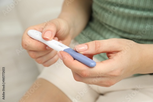 Woman holding pregnancy test indoors, closeup view