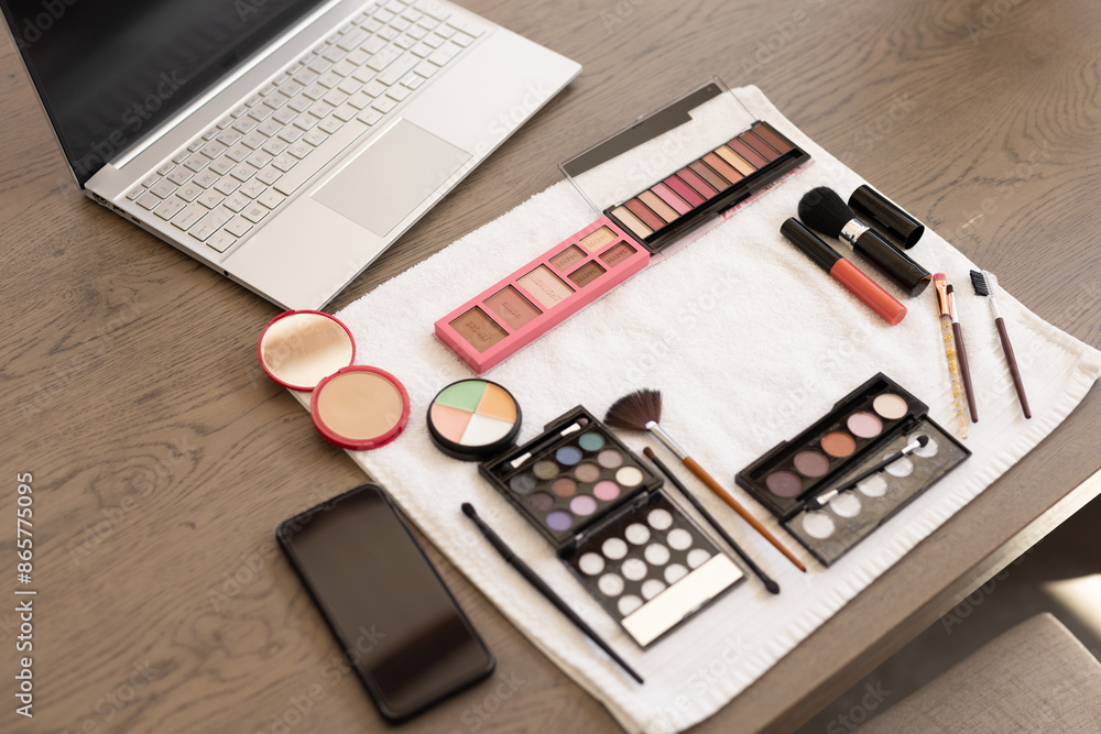 Makeup products and laptop on table, preparing for online beauty tutorial Makeup products and laptop on table, preparing for online beauty tutorial