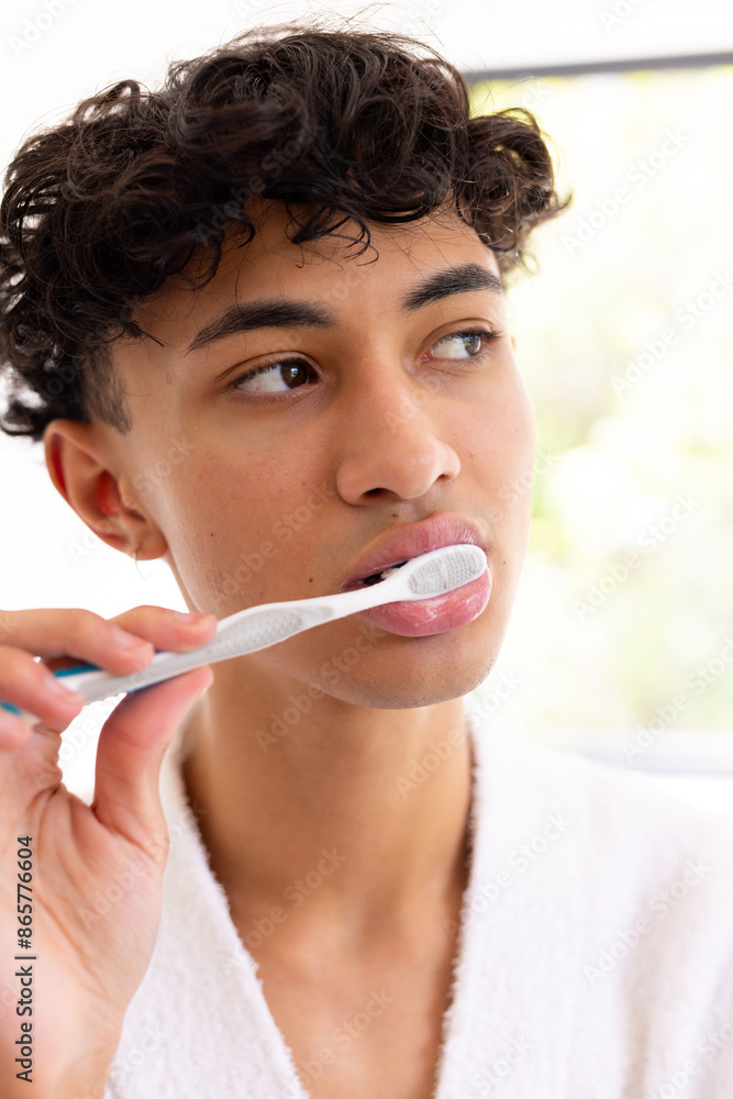 Brushing teeth, young young man in white robe focusing on oral hygiene Brushing teeth, young young man in white robe focusing on oral hygiene