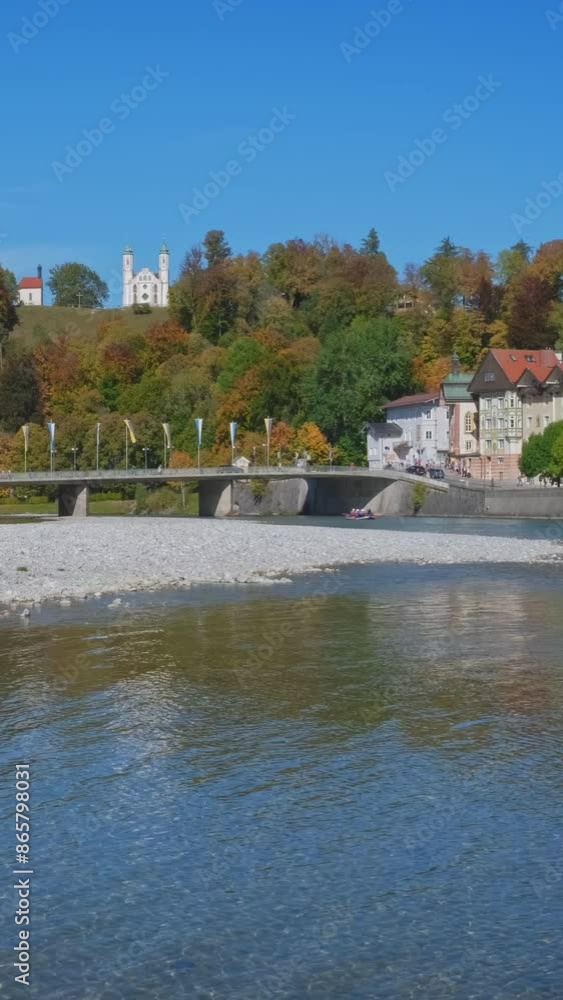 Golden autumn in famous tourist landmark town Bad Tolz. Landscape view of Isar river, shoal, trees, town bridge, Bavarian houses and Church. Bad Toelz, Bavaria, Germany. Horizontal panning Golden autumn in famous tourist landmark town Bad Tolz. Landscape view of Isar river, shoal, trees, town bridge, Bavarian houses and Church. Bad Toelz, Bavaria, Germany. Horizontal panning