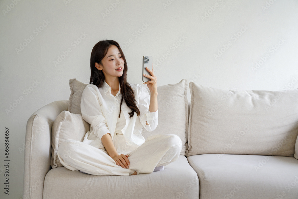白いシャツを着たスマートフォンを操作する若い女性 白いシャツを着たスマートフォンを操作する若い女性
