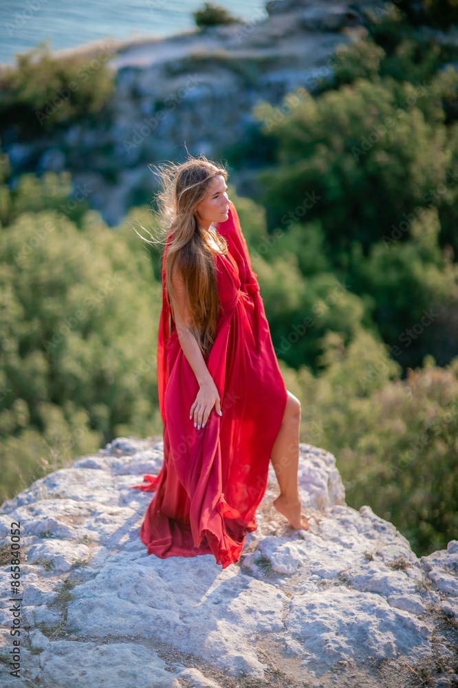Woman sunset sea red dress, back view a happy beautiful sensual woman in a red long dress posing on a rock high above the sea on sunset. Woman sunset sea red dress, back view a happy beautiful sensual woman in a red long dress posing on a rock high above the sea on sunset.