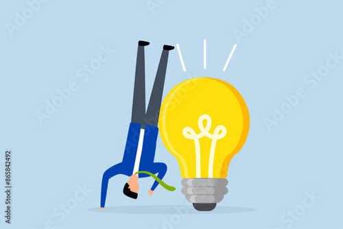 Think different to create unique idea, businessman who tries to think of idea with light bulb in another position.