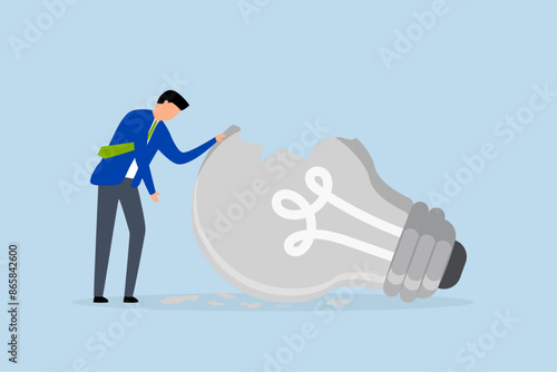 motivation after business failure, depressed businessman standing with old broken light bulb idea that failed miserably.
